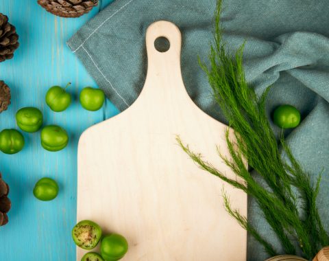top-view-wooden-board-scattered-sour-green-plums-with-cones-blue-wooden-table